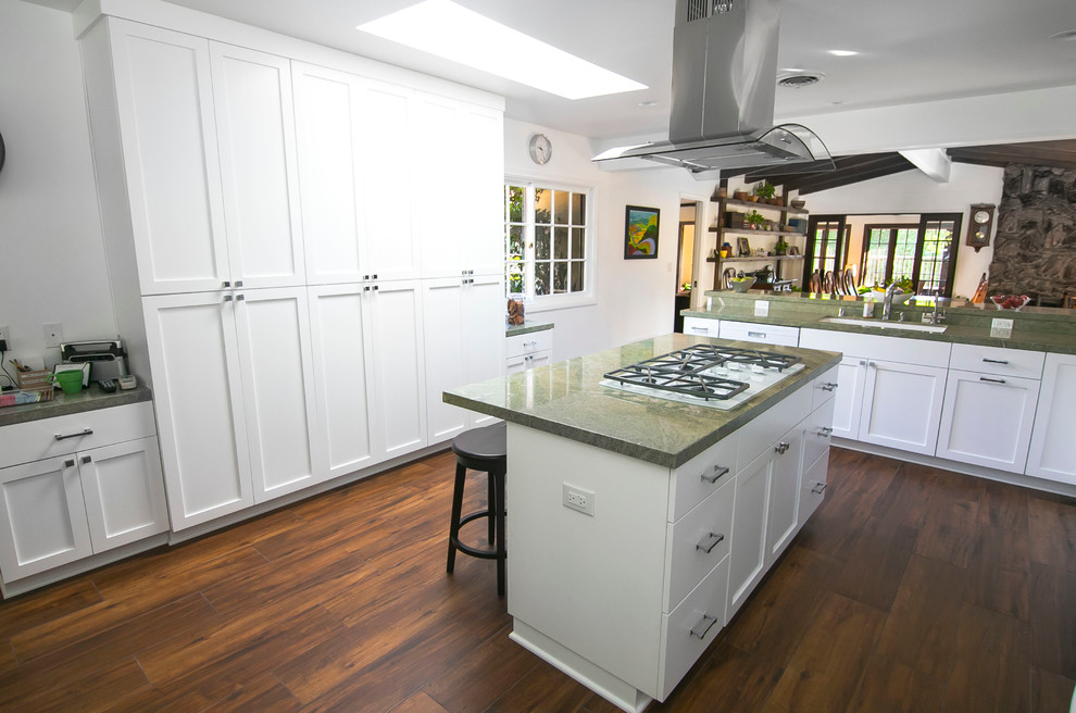 Large modern l-shaped eat-in kitchen in Los Angeles with a double-bowl sink, raised-panel cabinets, white cabinets, quartz benchtops, green splashback, stone slab splashback, white appliances, dark hardwood floors and with island.