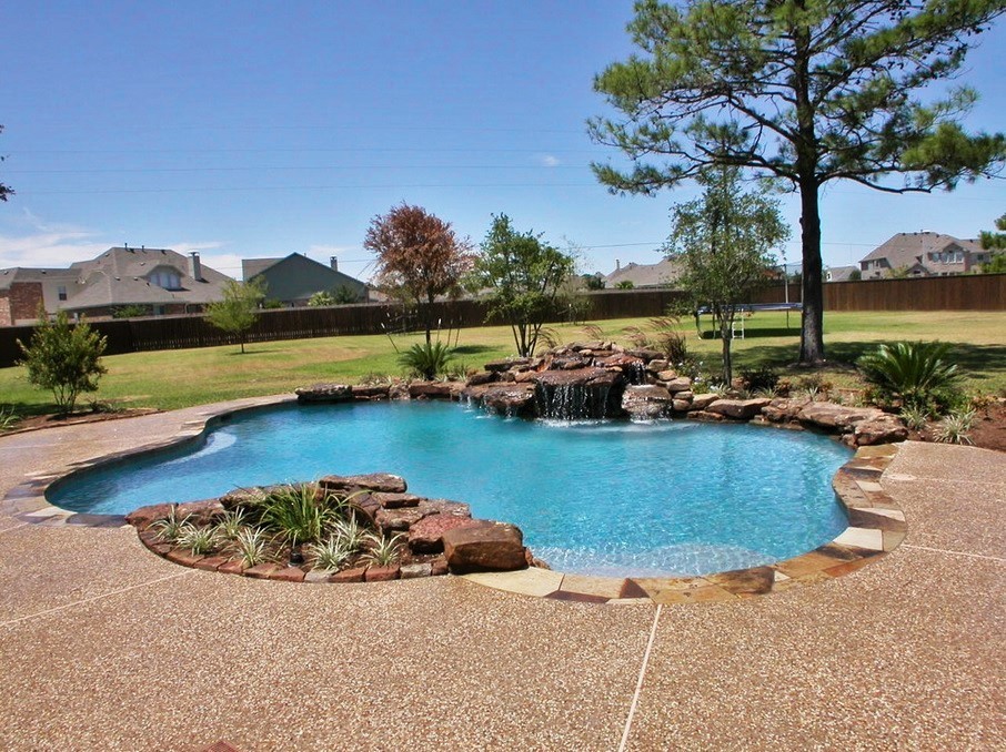 Photo of a large modern backyard custom-shaped pool in Houston with a water feature and stamped concrete.