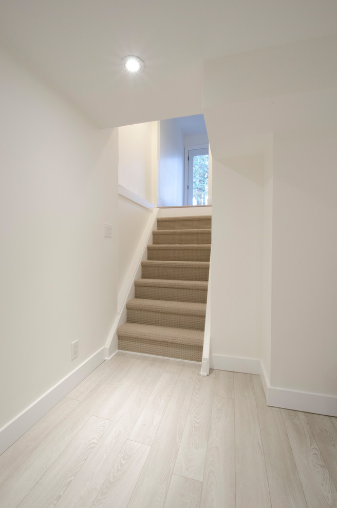 Inspiration for a mid-sized transitional look-out laminate floor and beige floor staircase remodel in Toronto with white walls