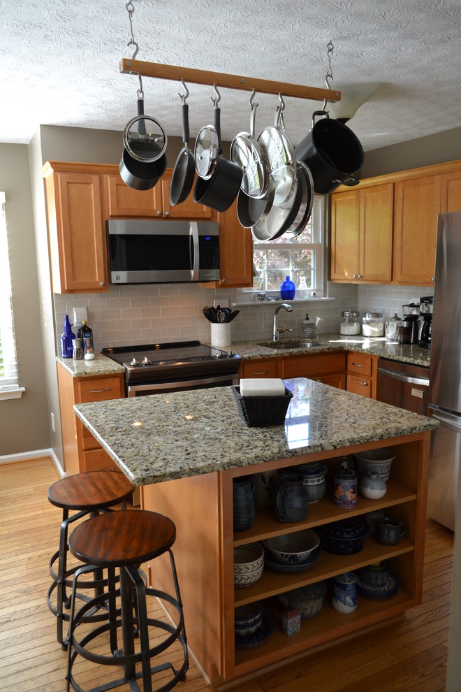 Eat-in kitchen - transitional l-shaped medium tone wood floor eat-in kitchen idea in Baltimore with an undermount sink, flat-panel cabinets, medium tone wood cabinets, granite countertops, gray backsplash, porcelain backsplash, stainless steel appliances and an island