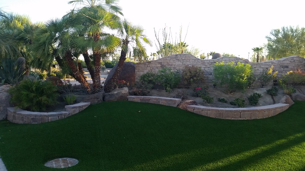 Expansive backyard partial sun xeriscape in Other with a retaining wall.