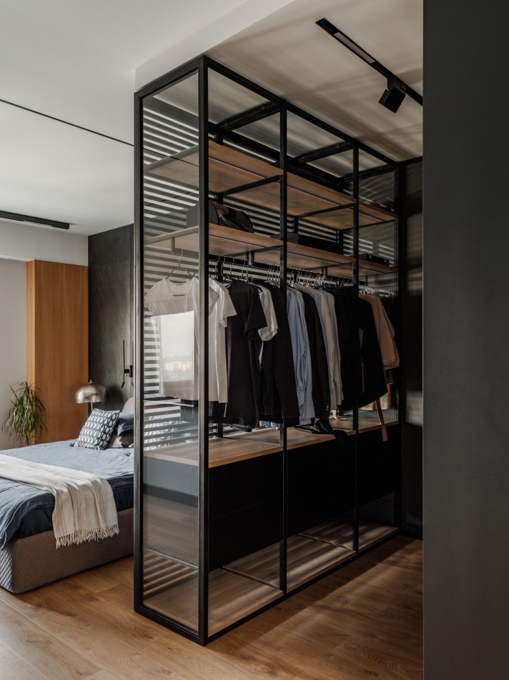 Photo of a medium sized contemporary gender neutral dressing room in Saint Petersburg with glass-front cabinets, black cabinets and exposed beams.