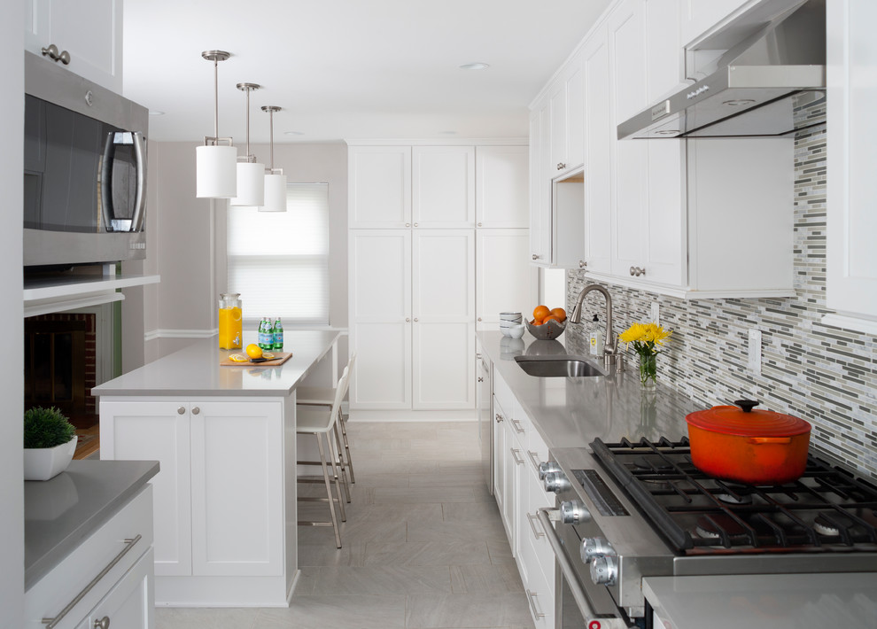 This is an example of a large transitional kitchen in DC Metro with white cabinets, beige splashback, glass tile splashback, stainless steel appliances and with island.