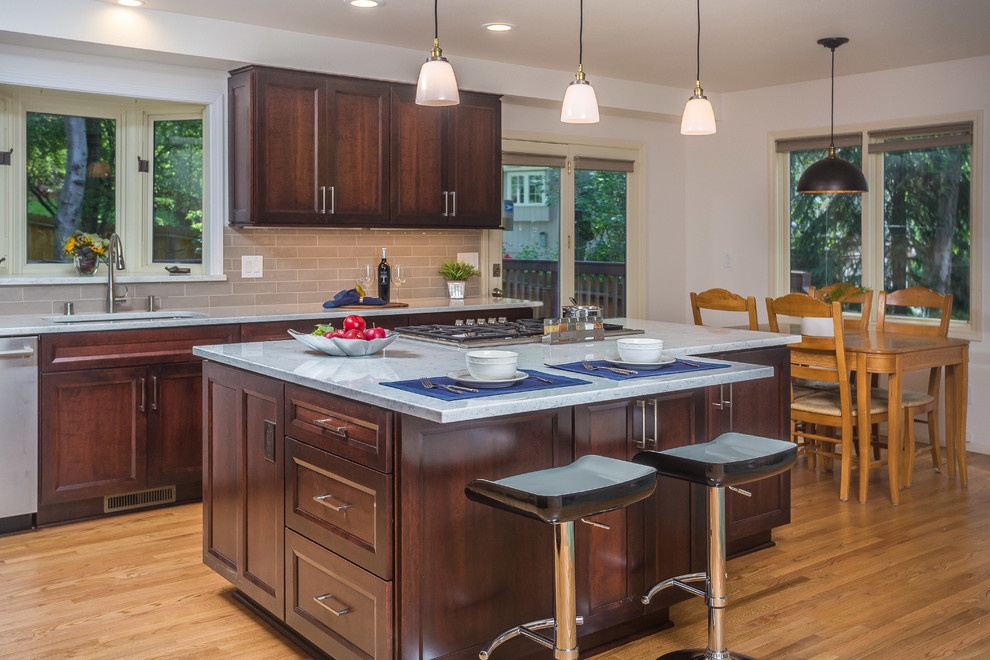 Inspiration for a mid-sized transitional l-shaped light wood floor open concept kitchen remodel with an undermount sink, recessed-panel cabinets, dark wood cabinets, quartz countertops, gray backsplash, subway tile backsplash, stainless steel appliances and an island