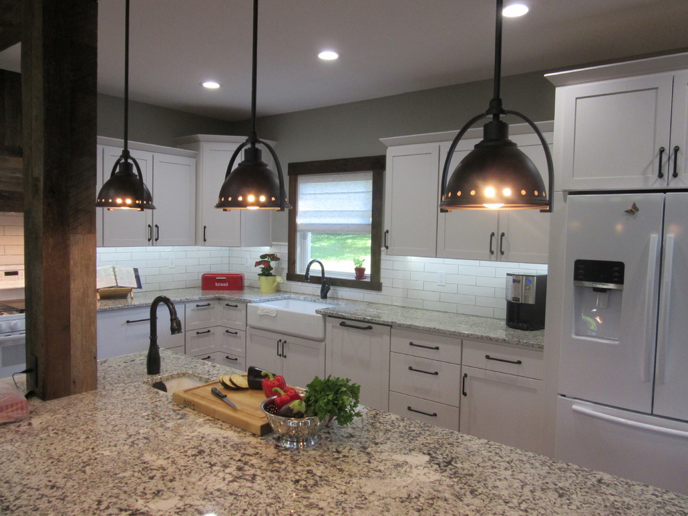 Design ideas for a country l-shaped eat-in kitchen in Other with a farmhouse sink, shaker cabinets, white cabinets, granite benchtops, white splashback, porcelain splashback, white appliances, dark hardwood floors and with island.
