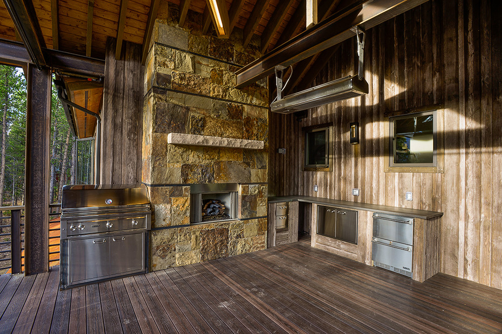 Large mountain style backyard outdoor kitchen deck photo in Denver with a roof extension