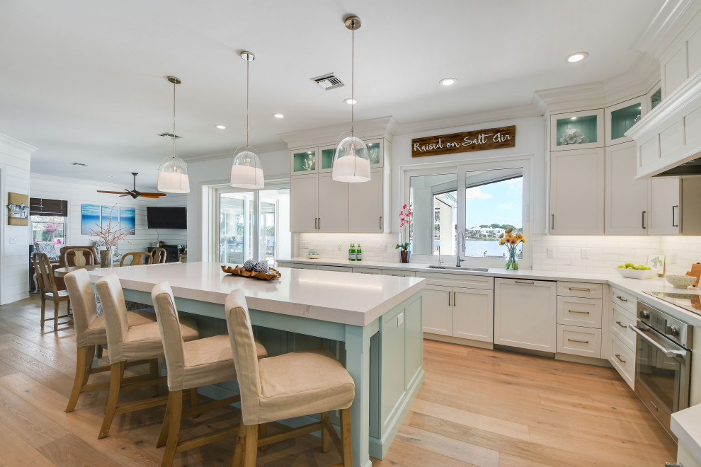 Mid-sized beach style u-shaped eat-in kitchen photo in Other with shaker cabinets, quartz countertops, white backsplash, porcelain backsplash, stainless steel appliances, an island and white countertops