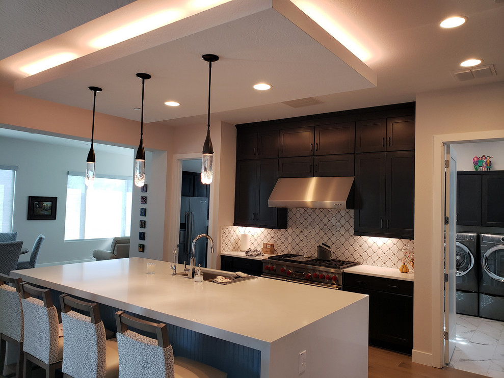 Example of a large transitional porcelain tile eat-in kitchen design in Phoenix with shaker cabinets, quartz countertops, white backsplash, mosaic tile backsplash, stainless steel appliances, an island, white countertops, an undermount sink and dark wood cabinets