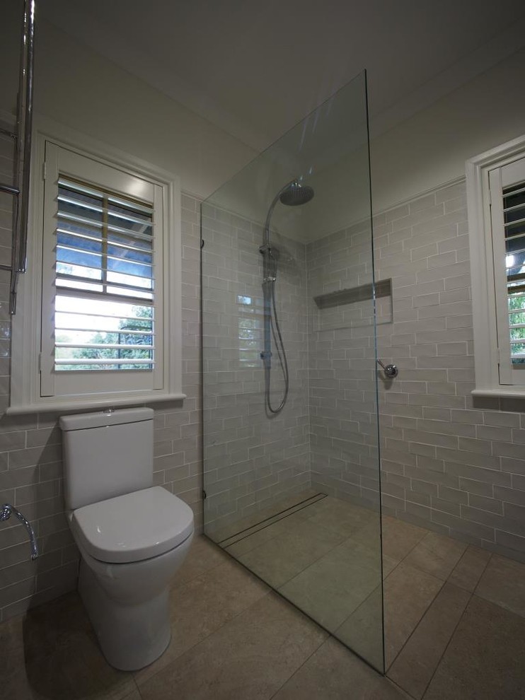 Photo of a large traditional 3/4 bathroom in Brisbane with beaded inset cabinets, white cabinets, a curbless shower, a one-piece toilet, beige tile, ceramic tile, beige walls, porcelain floors, an undermount sink and granite benchtops.