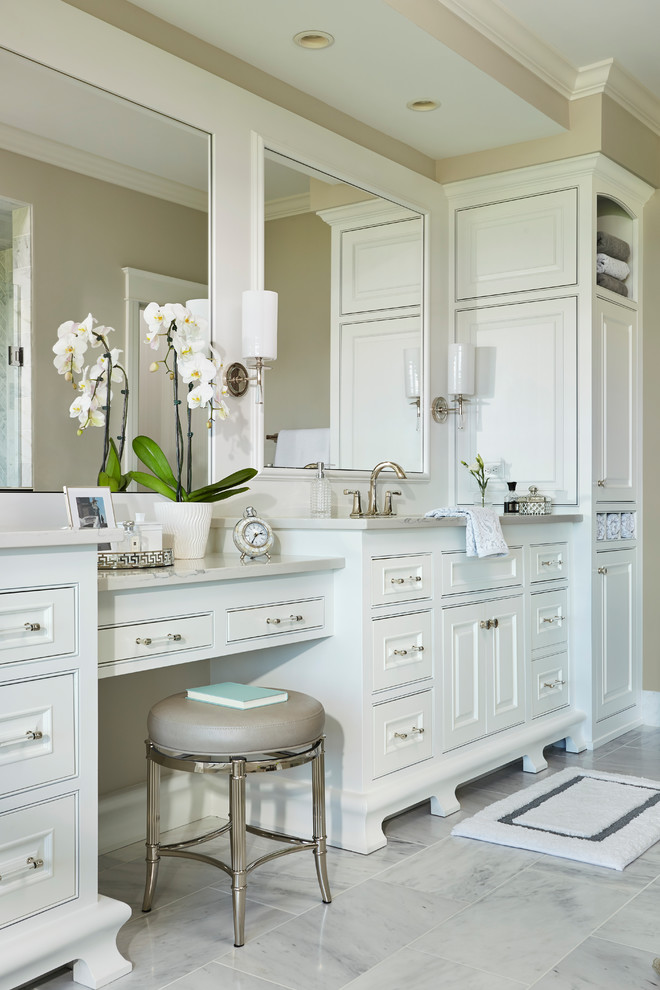 This is an example of an expansive transitional master bathroom in Minneapolis with recessed-panel cabinets, white cabinets, a freestanding tub, a corner shower, a one-piece toilet, gray tile, marble, beige walls, marble floors, an undermount sink, quartzite benchtops, white floor, a hinged shower door and white benchtops.