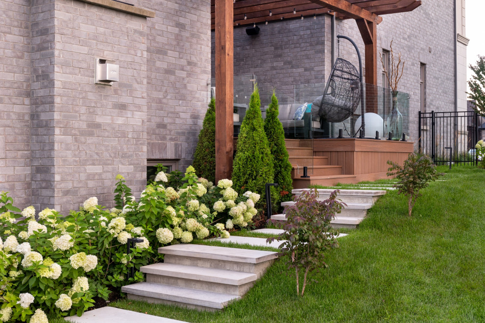 Imagen de jardín clásico renovado de tamaño medio en verano en patio lateral con camino de entrada, exposición parcial al sol, adoquines de hormigón y con metal