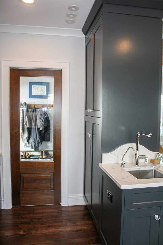 Mid-sized transitional single-wall dark wood floor and brown floor open concept kitchen photo with a drop-in sink, beaded inset cabinets, black cabinets, granite countertops, gray backsplash, ceramic backsplash, stainless steel appliances, an island and white countertops