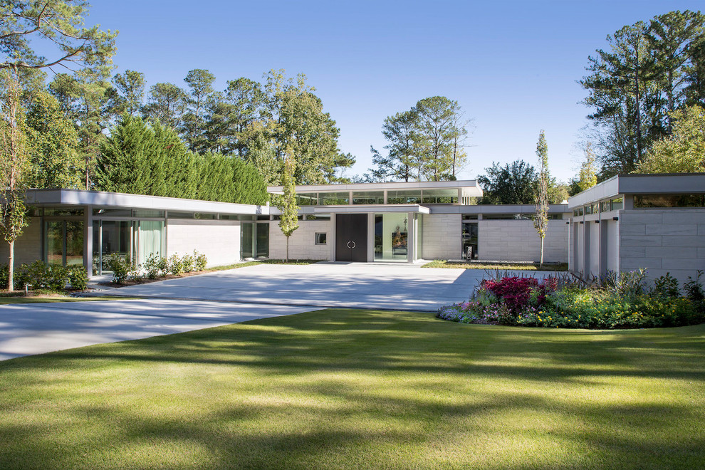 This is an example of a large midcentury two-storey grey house exterior in Atlanta with stone veneer and a flat roof.