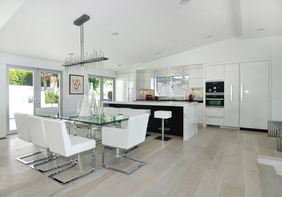 Inspiration for a large contemporary galley eat-in kitchen in Orange County with an undermount sink, flat-panel cabinets, white cabinets, marble benchtops, white splashback, stainless steel appliances, light hardwood floors, with island, marble splashback and brown floor.