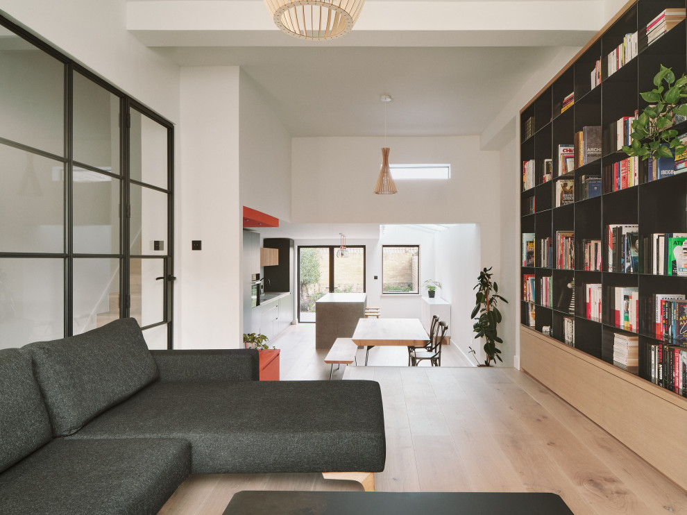 Esempio di un grande soggiorno minimalista aperto con libreria, pareti bianche, nessuna TV, parquet chiaro, nessun camino e pavimento marrone
