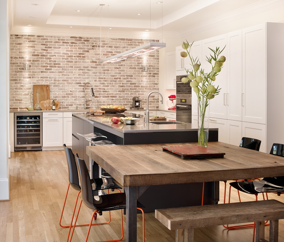 Photo of a large contemporary l-shaped eat-in kitchen in Atlanta with shaker cabinets, with island, a single-bowl sink, white cabinets, stainless steel appliances, light hardwood floors, quartz benchtops, multi-coloured splashback, brick splashback, beige floor and grey benchtop.