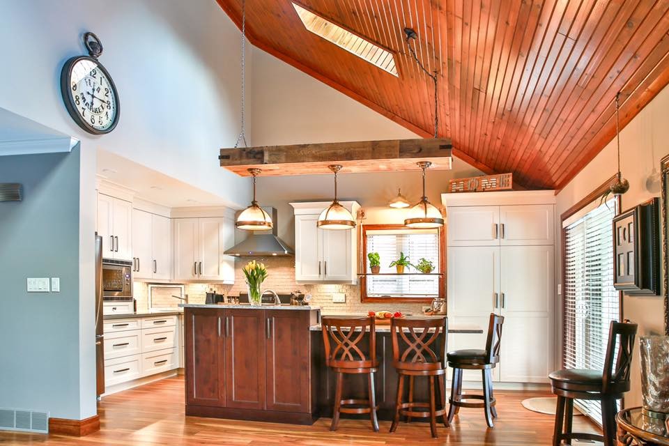 Mid-sized transitional l-shaped medium tone wood floor and brown floor eat-in kitchen photo with an undermount sink, white backsplash, subway tile backsplash, paneled appliances, shaker cabinets, white cabinets, quartzite countertops and an island