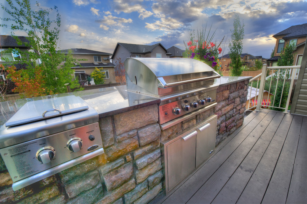 Example of a small backyard outdoor kitchen deck design in Calgary