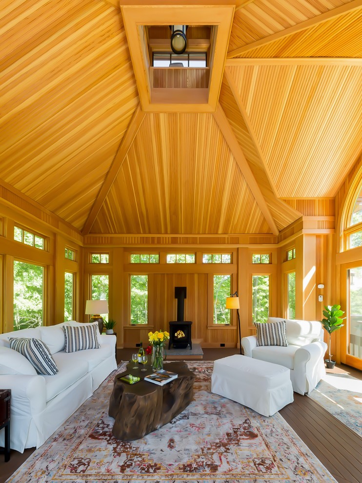 Country sunroom in Boston with dark hardwood floors, a wood stove and a skylight.