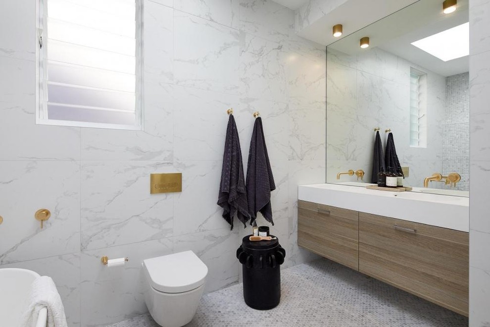 Mid-sized contemporary master bathroom in Sydney with furniture-like cabinets, light wood cabinets, a freestanding tub, an open shower, a one-piece toilet, white tile, ceramic tile, white walls, mosaic tile floors, an integrated sink, marble benchtops, grey floor, an open shower and white benchtops.