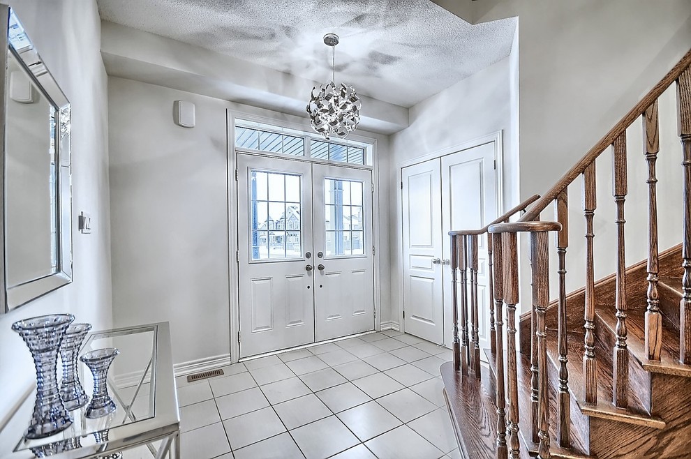 Inspiration for a mid-sized transitional ceramic tile and beige floor foyer remodel in Toronto with beige walls and a white front door