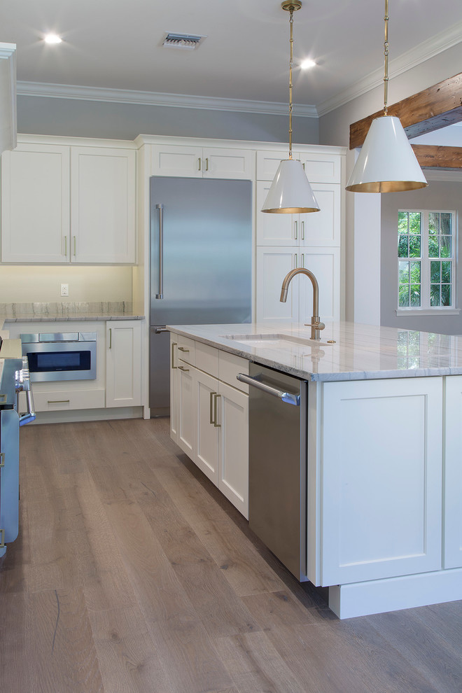 Inspiration for a large transitional u-shaped light wood floor eat-in kitchen remodel in Orlando with a farmhouse sink, shaker cabinets, white cabinets, granite countertops, white backsplash, stainless steel appliances and an island