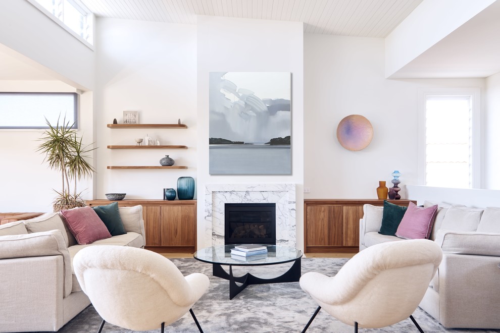 This is an example of a contemporary open concept living room in Sydney with white walls, medium hardwood floors, a standard fireplace and brown floor.