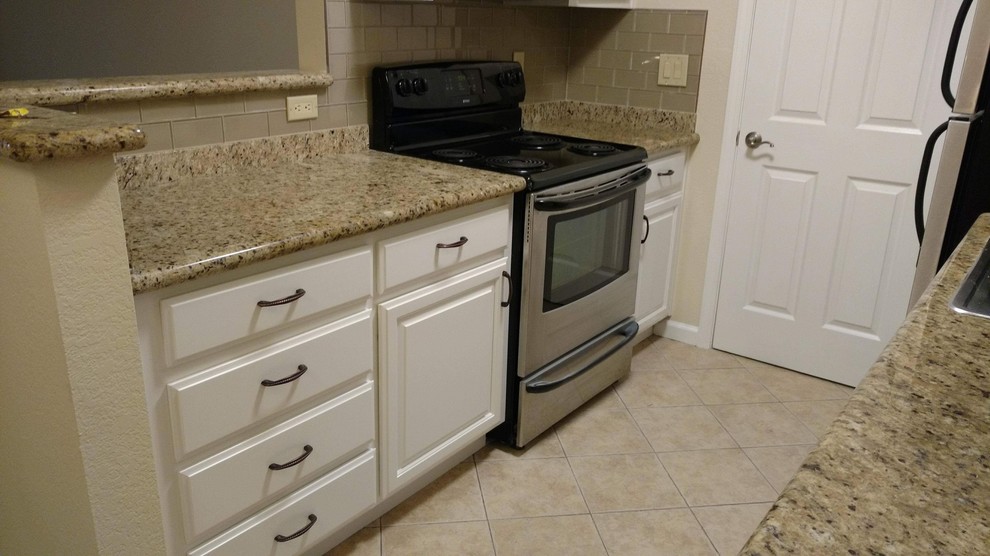 Enclosed kitchen - small transitional galley porcelain tile and beige floor enclosed kitchen idea in San Francisco with a drop-in sink, raised-panel cabinets, white cabinets, granite countertops, beige backsplash, glass tile backsplash, stainless steel appliances, no island and multicolored countertops