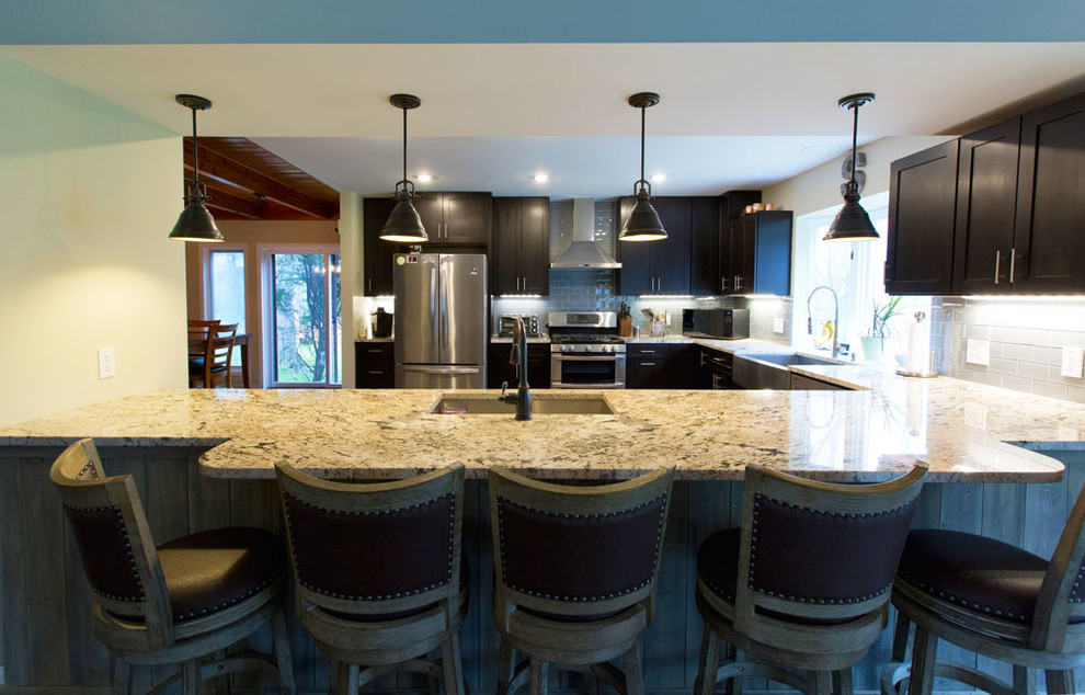 Inspiration for a large transitional u-shaped light wood floor and brown floor enclosed kitchen remodel in Cleveland with a farmhouse sink, shaker cabinets, dark wood cabinets, granite countertops, gray backsplash, glass tile backsplash, stainless steel appliances, a peninsula and beige countertops
