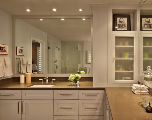 This contemporary bathroom features a large mirror, frosted glass-faced cabinets, and two sinks, one on either side of the L-shaped vanity.