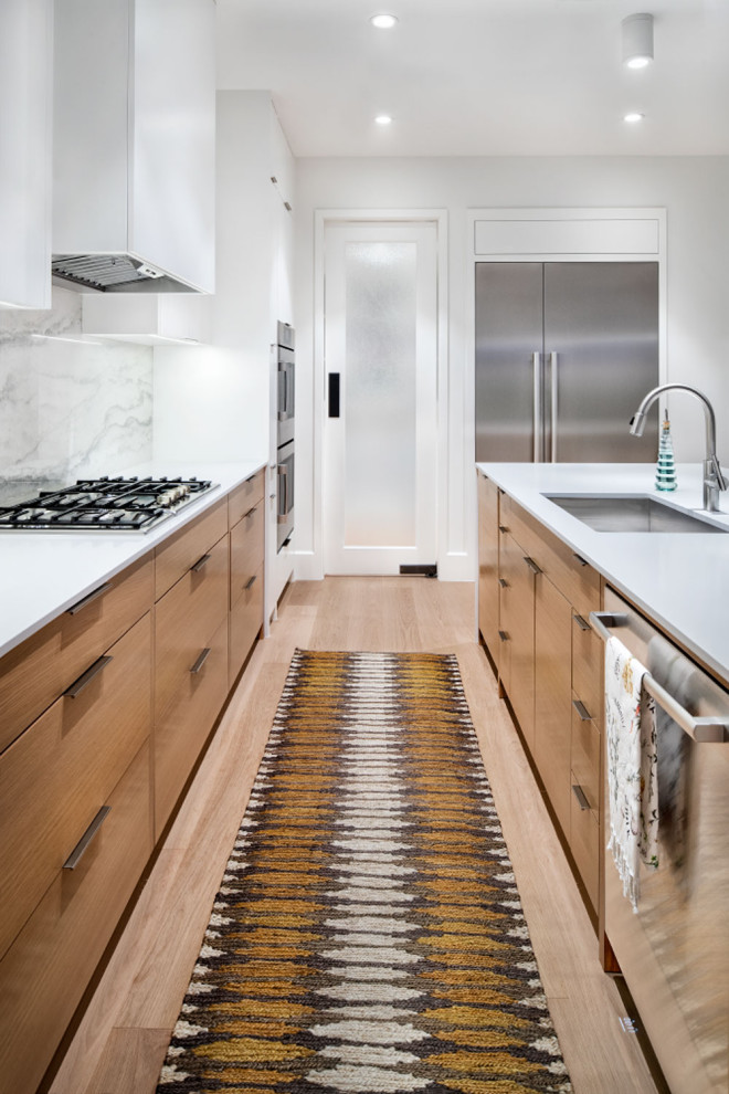 Mid-sized contemporary single-wall eat-in kitchen in Austin with an undermount sink, flat-panel cabinets, medium wood cabinets, solid surface benchtops, white splashback, porcelain splashback, stainless steel appliances, light hardwood floors, with island, beige floor, white benchtop and timber.