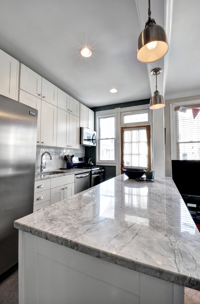 Design ideas for a mid-sized transitional galley eat-in kitchen in DC Metro with an undermount sink, shaker cabinets, white cabinets, quartzite benchtops, white splashback, subway tile splashback, stainless steel appliances, porcelain floors and with island.