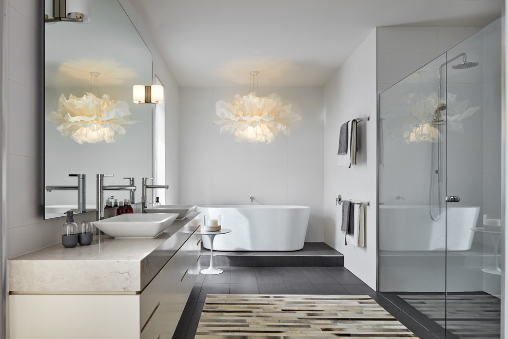 This is an example of a contemporary master bathroom in Melbourne with flat-panel cabinets, white cabinets, a freestanding tub, an alcove shower, gray tile, grey walls, a vessel sink, marble benchtops, grey floor and a hinged shower door.