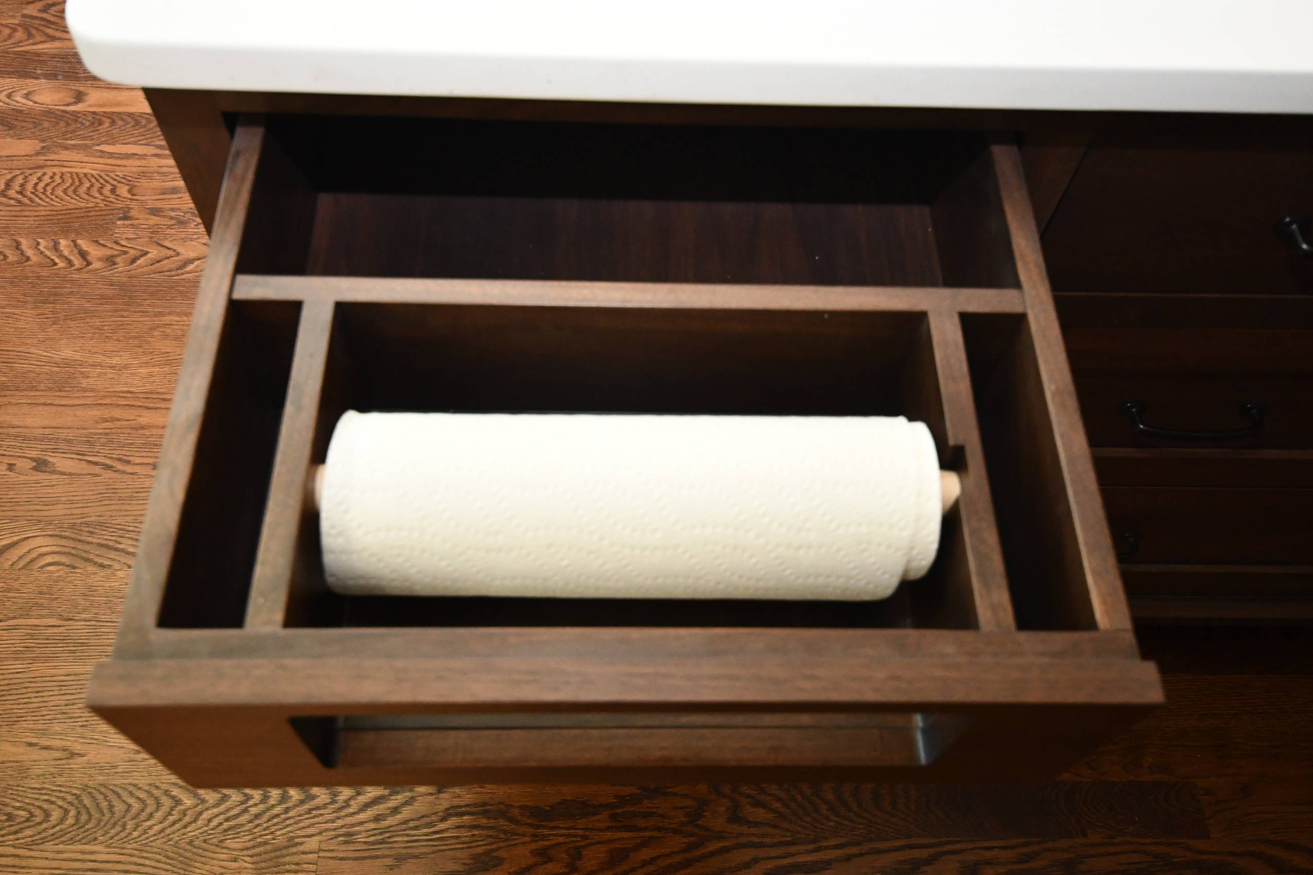 custom, built-in paper towel holder inside of white kitchen cabinets with  raised p…