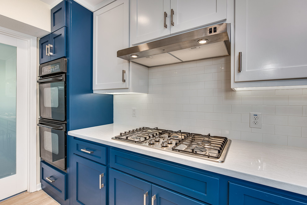 Inspiration for a mid-sized modern l-shaped eat-in kitchen in Austin with a double-bowl sink, flat-panel cabinets, blue cabinets, quartz benchtops, grey splashback, cement tile splashback, stainless steel appliances, porcelain floors, with island, white floor and grey benchtop.
