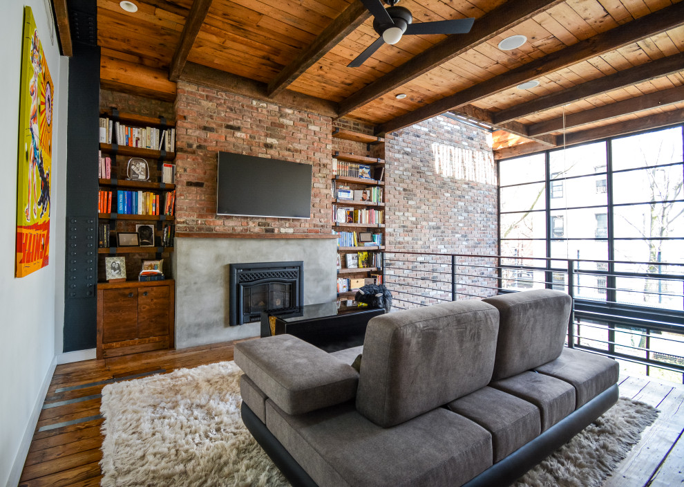 Mid-sized industrial loft-style family room in Other with white walls, medium hardwood floors, a standard fireplace, a concrete fireplace surround, brown floor, exposed beam and brick walls.