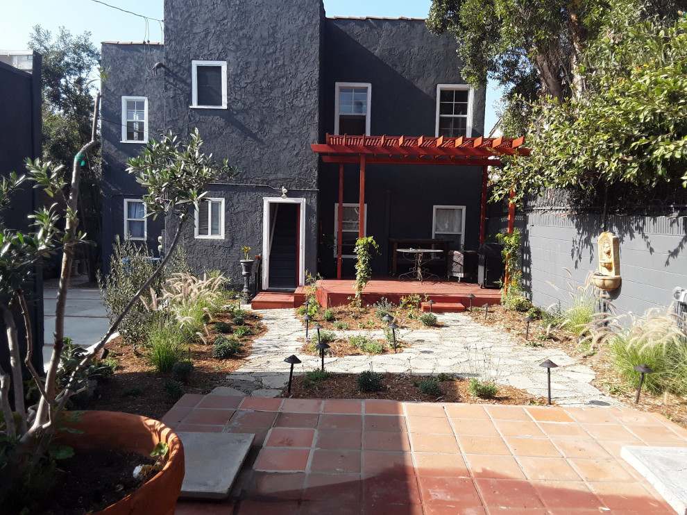 Photo of a small eclectic back patio in Los Angeles with a water feature, concrete paving and a pergola.