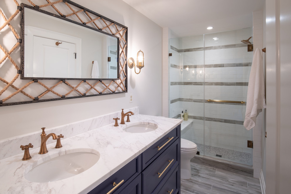 Mid-sized beach style kids bathroom in Baltimore with recessed-panel cabinets, blue cabinets, white tile, subway tile, white walls, ceramic floors, marble benchtops, grey floor, a sliding shower screen and white benchtops.