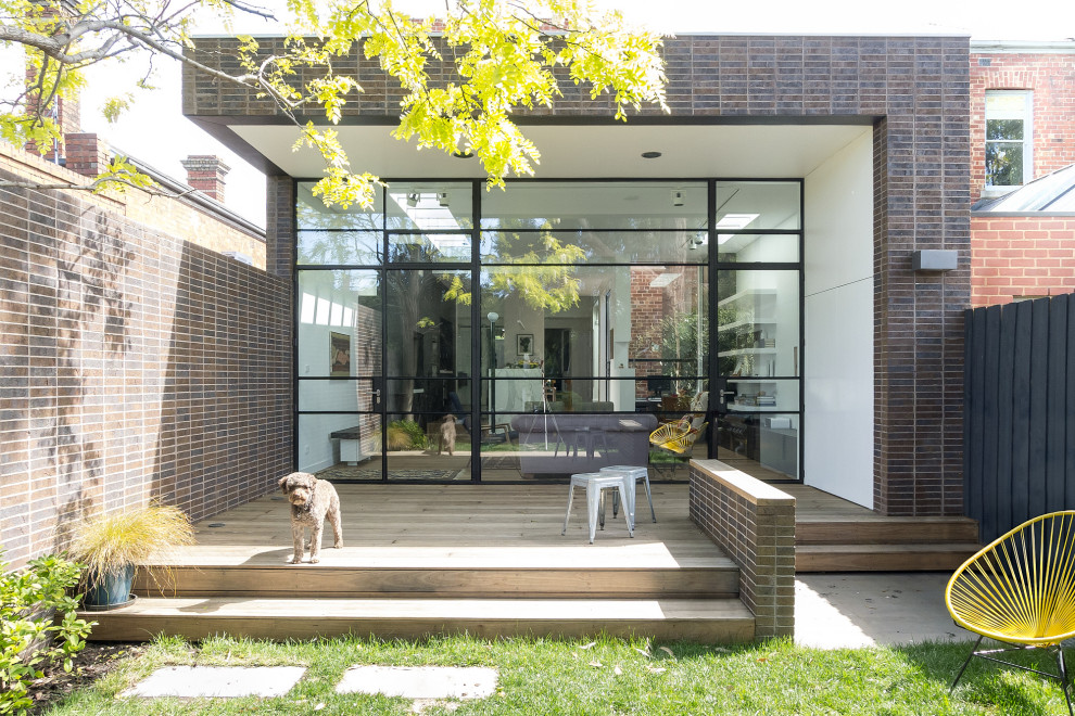 Inspiration for a contemporary backyard and ground level deck in Melbourne with a roof extension.