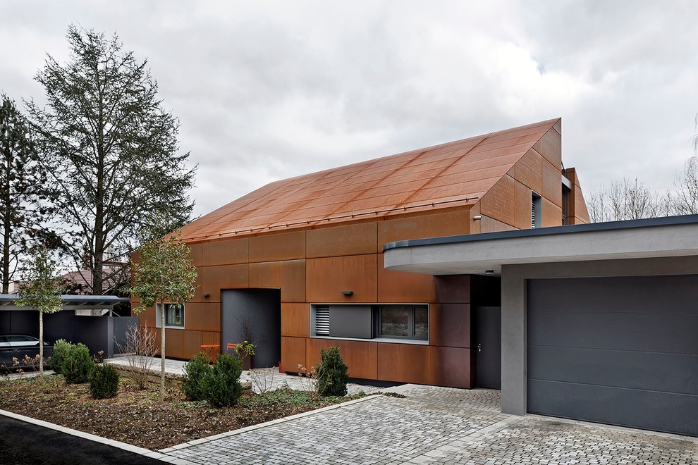 This is an example of a mid-sized contemporary two-storey red exterior in Stuttgart with a gable roof and metal siding.