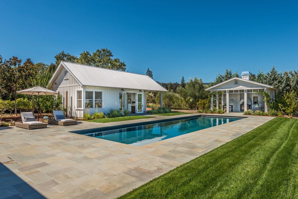Inspiration for a country rectangular lap pool in San Francisco with a pool house and natural stone pavers.
