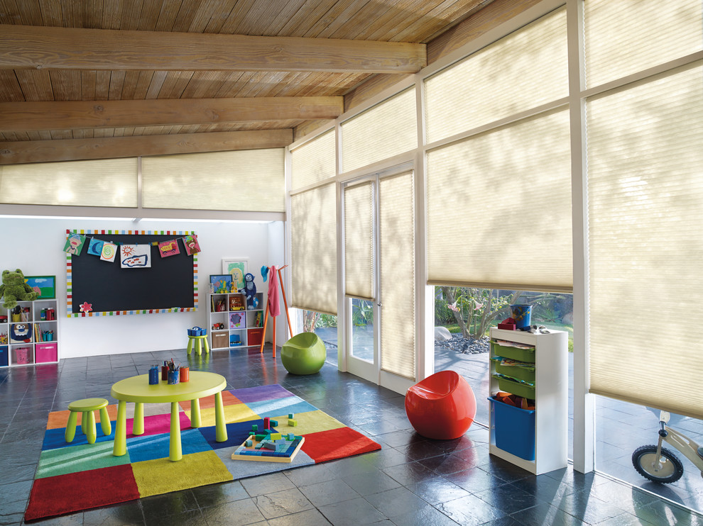 Inspiration for an expansive midcentury gender-neutral kids' playroom for kids 4-10 years old in New York with white walls and slate floors.