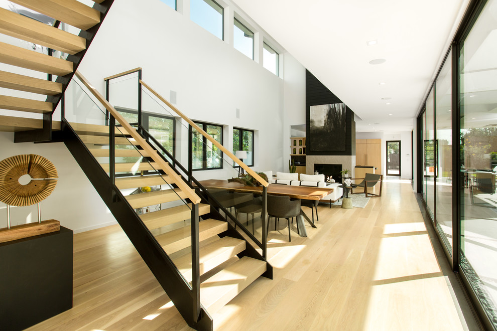 Photo of a mid-sized contemporary wood u-shaped staircase in Los Angeles with open risers and glass railing.