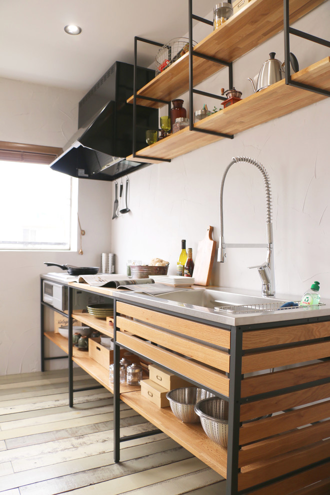 Photo of an industrial single-wall open plan kitchen in Other with a single-bowl sink, open cabinets, stainless steel benchtops, painted wood floors, with island and grey floor.