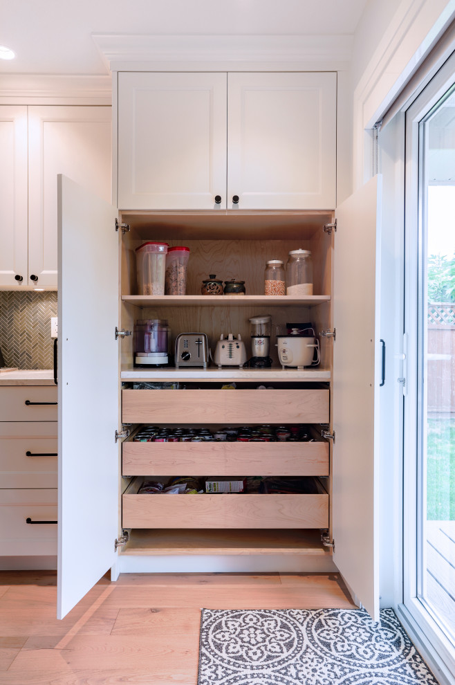 Medium sized traditional l-shaped kitchen pantry in Vancouver with a submerged sink, recessed-panel cabinets, white cabinets, engineered stone countertops, grey splashback, stone tiled splashback, stainless steel appliances, light hardwood flooring, an island, beige floors and grey worktops.