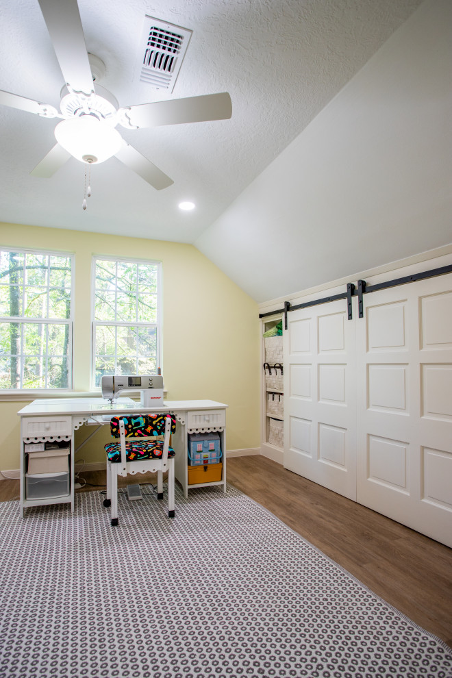 Large modern craft room in Houston with yellow walls, laminate floors, a freestanding desk, brown floor and vaulted.