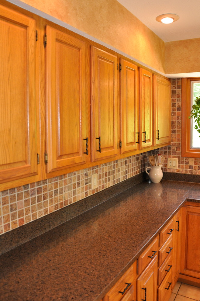 Mid-sized transitional l-shaped ceramic tile eat-in kitchen photo in Cincinnati with an undermount sink, raised-panel cabinets, medium tone wood cabinets, quartz countertops, multicolored backsplash, stone tile backsplash, stainless steel appliances and an island
