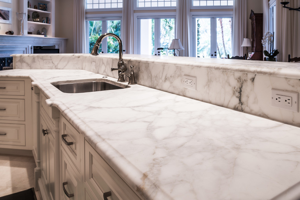 Inspiration for a large transitional u-shaped limestone floor and white floor open concept kitchen remodel in Orlando with an undermount sink, raised-panel cabinets, white cabinets, marble countertops, gray backsplash, marble backsplash, stainless steel appliances and two islands