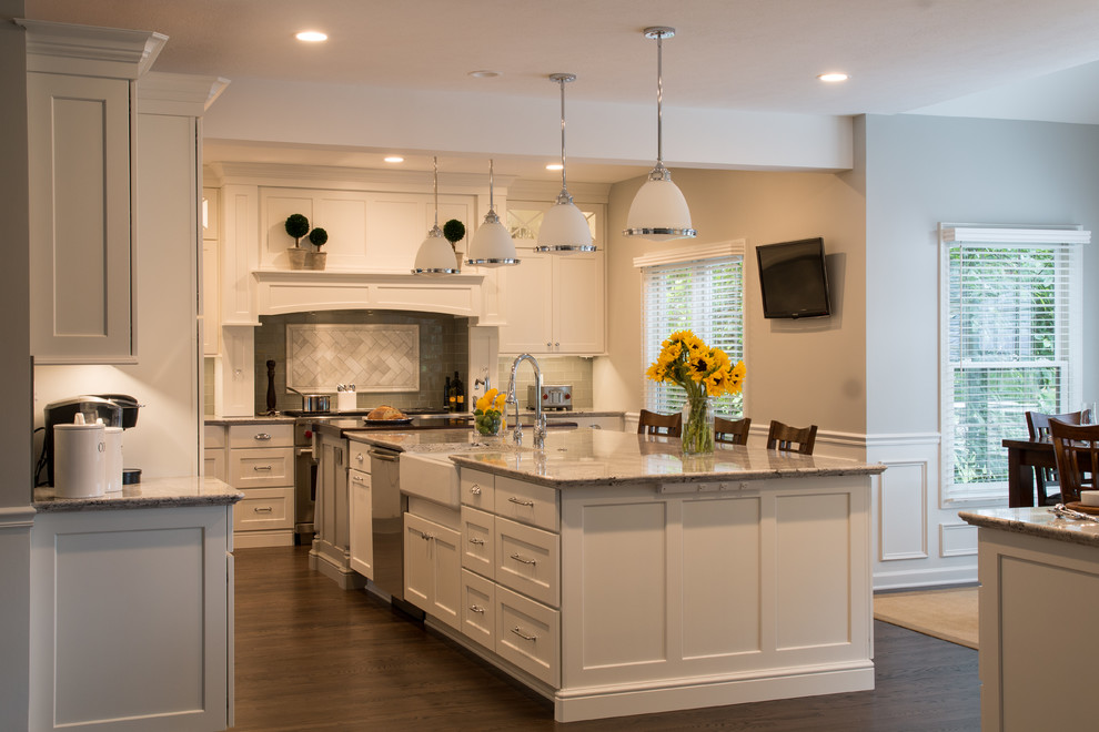Example of a transitional dark wood floor and brown floor kitchen design with a farmhouse sink, recessed-panel cabinets, white cabinets, quartz countertops, stainless steel appliances and two islands