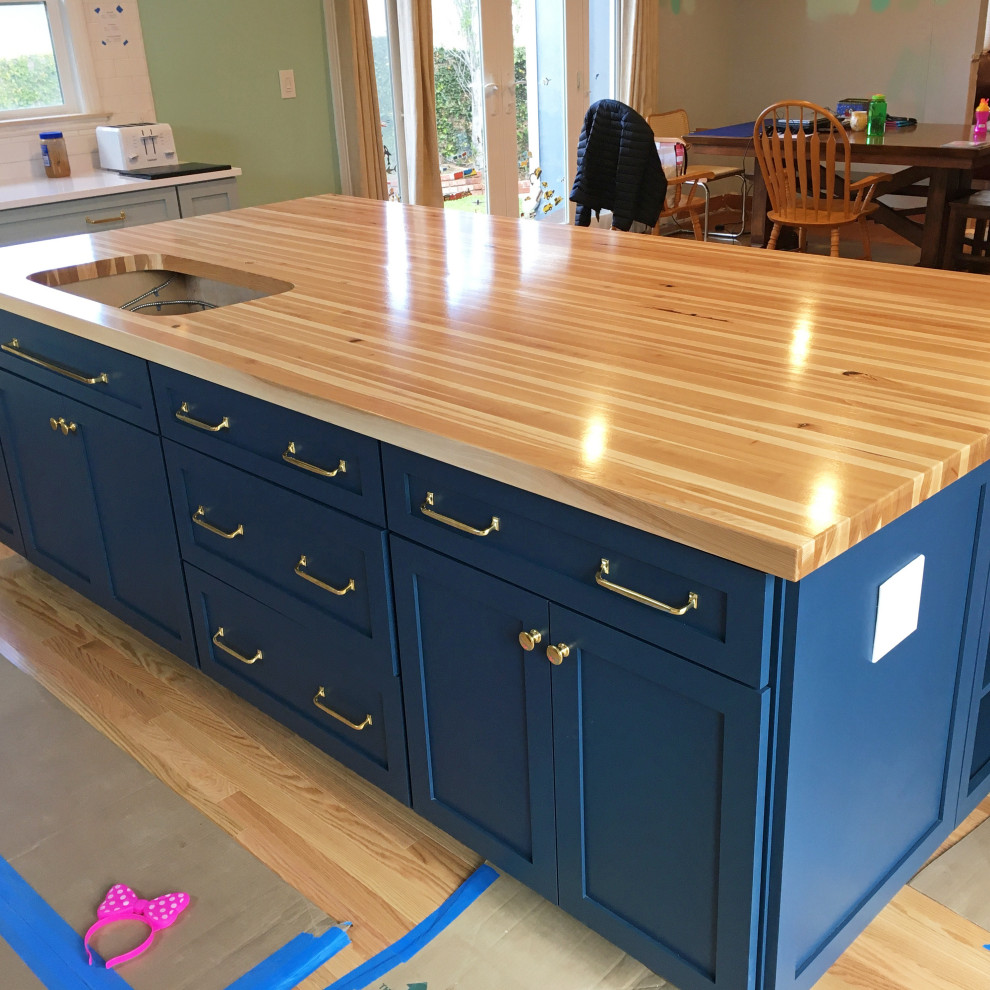 Farmhouse l-shaped kitchen/diner in Los Angeles with recessed-panel cabinets, blue cabinets, wood worktops, light hardwood flooring, an island, yellow floors and yellow worktops.